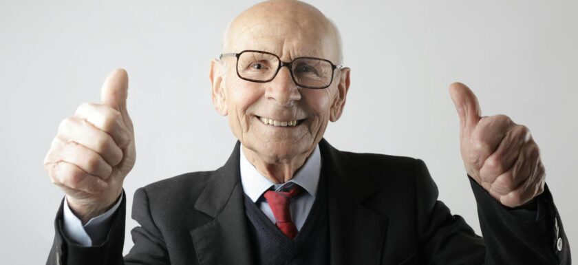 Positive senior man in eyeglasses showing thumbs up and looking at camera