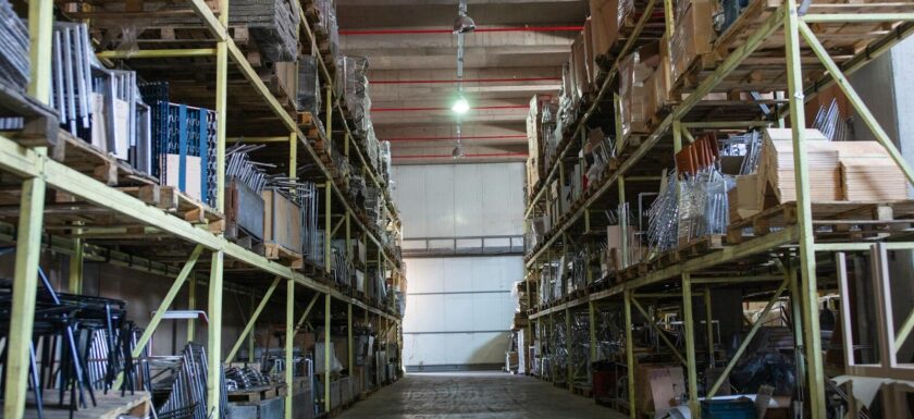 Wide aisle in a spacious warehouse filled with industrial metal shelving units.